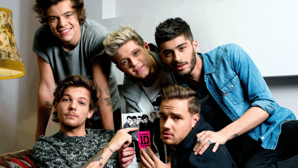 ESTA ES UNA IMAGEN QUE MUESTRA A LOS CINO INTEGRANTES DE ONE DIRECTION, POSANDO PARA UNA FOTO GRUPAL, MOSTRANDO EN EL MEDIO UNA IMAGEN SUYA CON EL TITULO DE ONE DIRECTION.