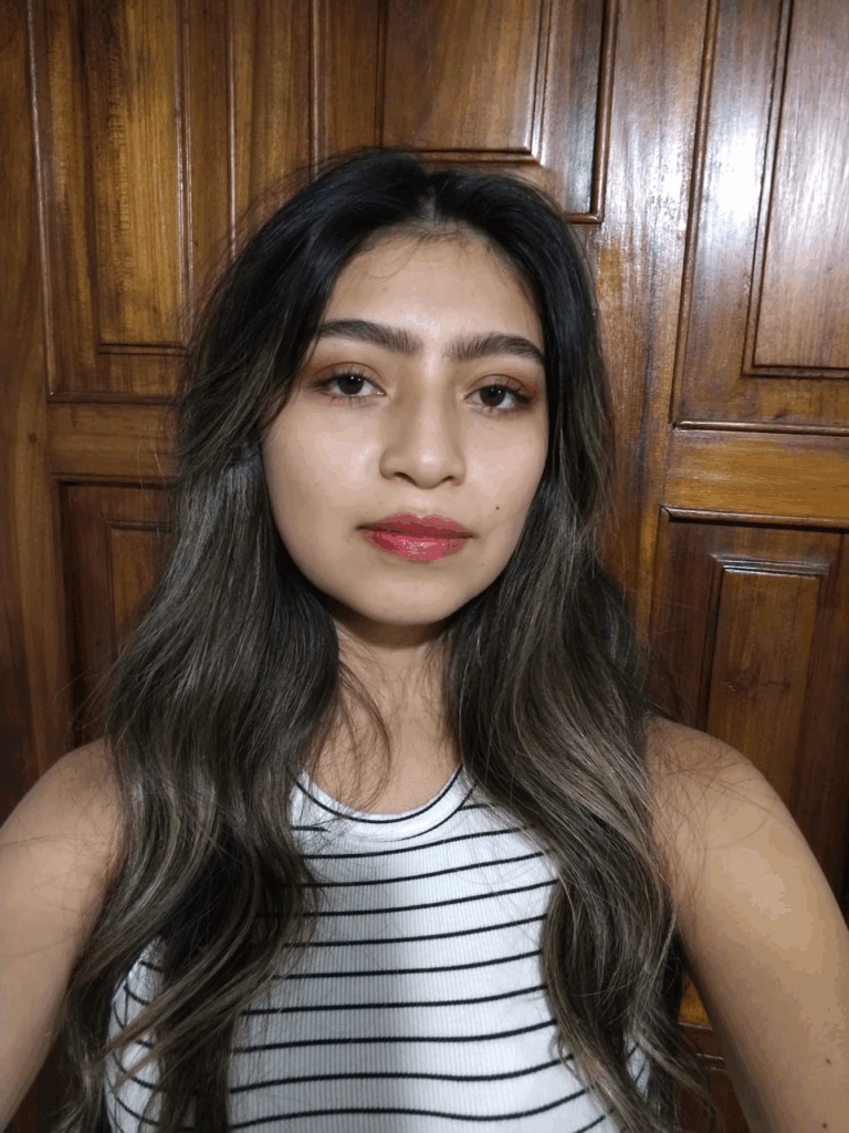 Mujer de 18 años de cabello largo, de ojos cafés con camiseta blanca de rayas negras.