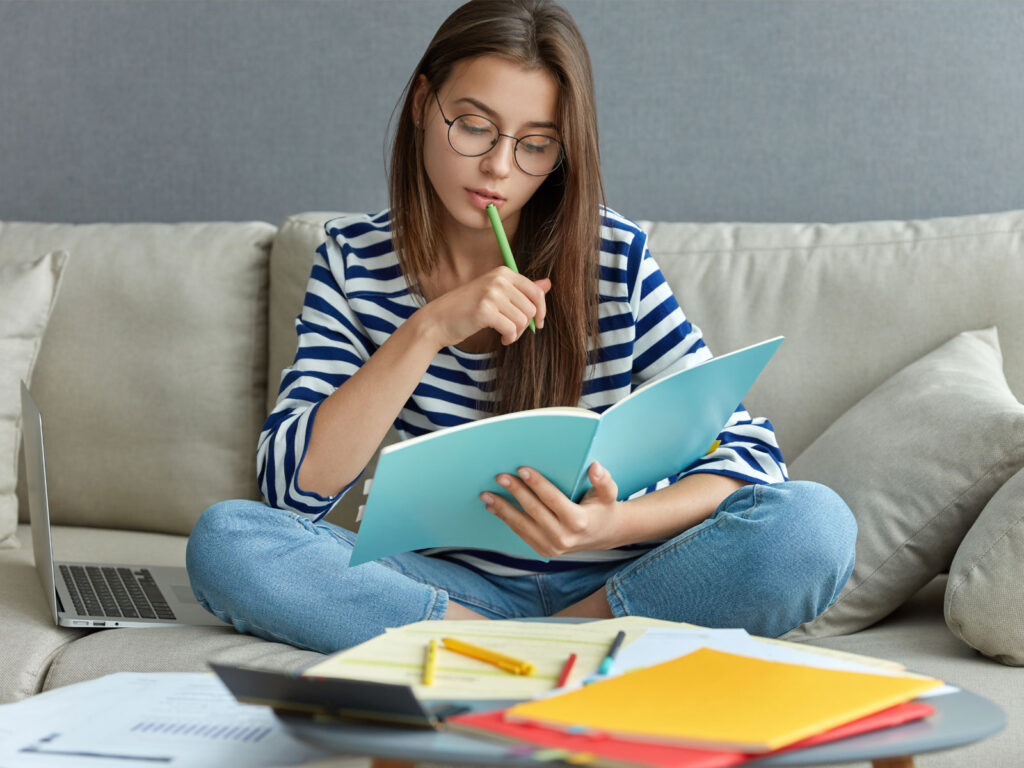 Foto de señorita sentada en un sofá muy cómoda estudiando